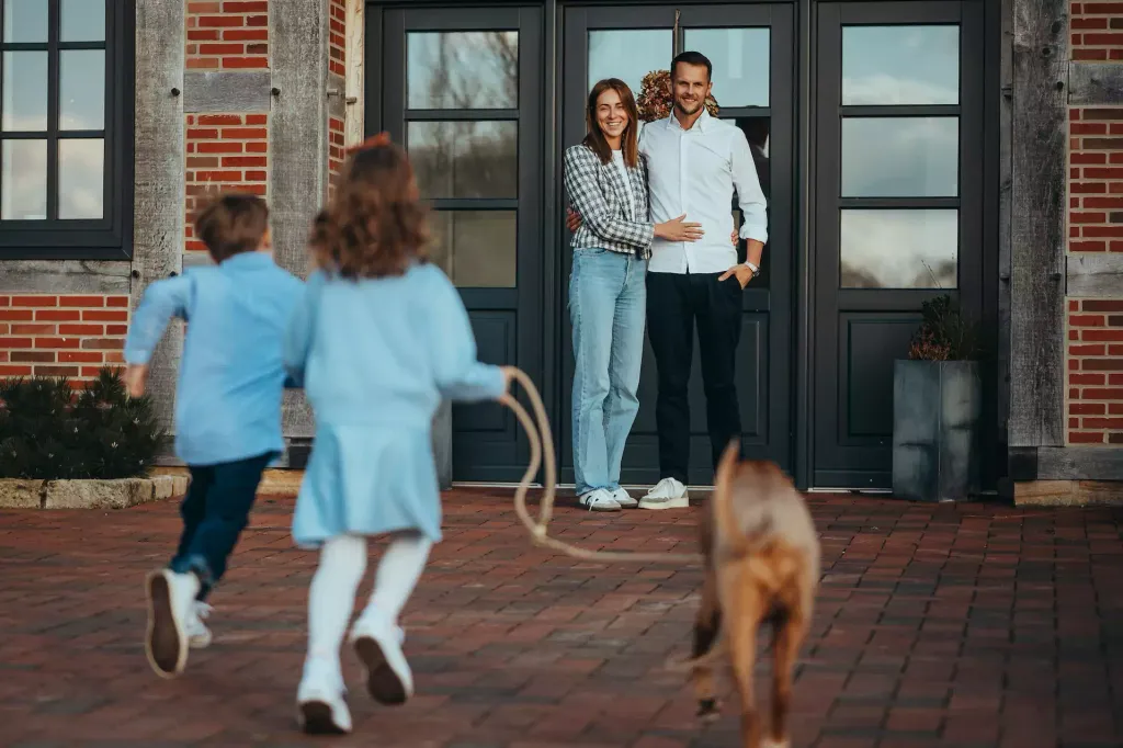 A happy family with two children and a dog in front of a brick house