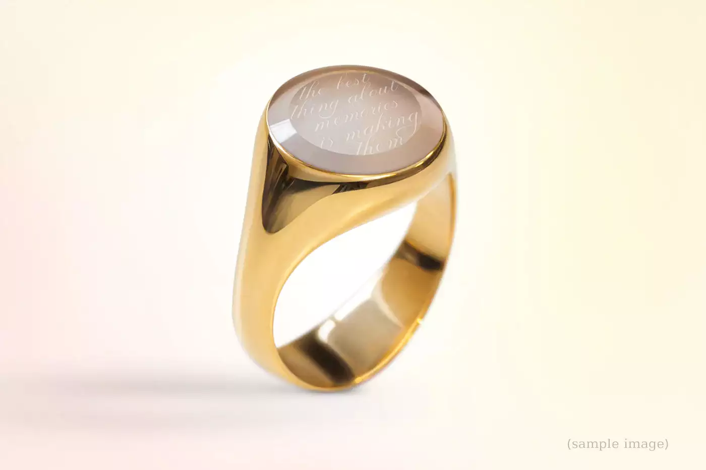 Nahaufnahme eines Siegelrings mit personalisiertem, rundem Edelstein und feiner Gravur vor sanftem Pastell-Verlauf